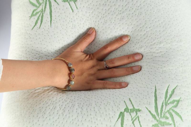 A hand pressing into the soft knit cover of the pillow